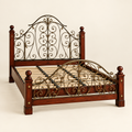 Ornate solid mahogany and metal scrollwork bed frame in a clean studio