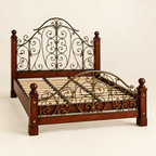 Ornate solid mahogany and metal scrollwork bed frame in a clean studio